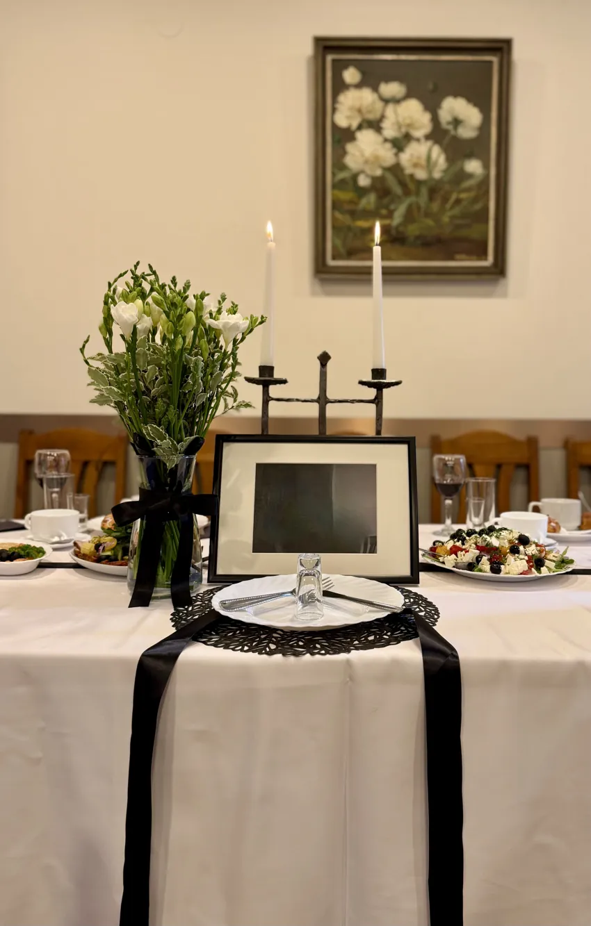 Piemiņas vieta galda galā ar sveci un ziediem